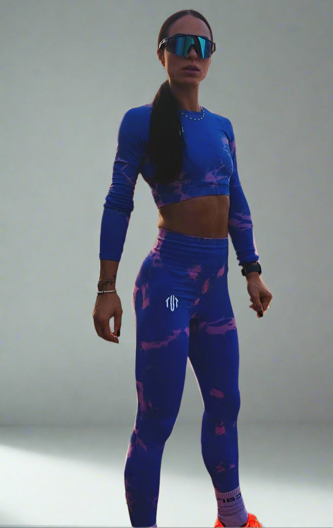 Person wearing a blue athletic outfit on a beach at sunset