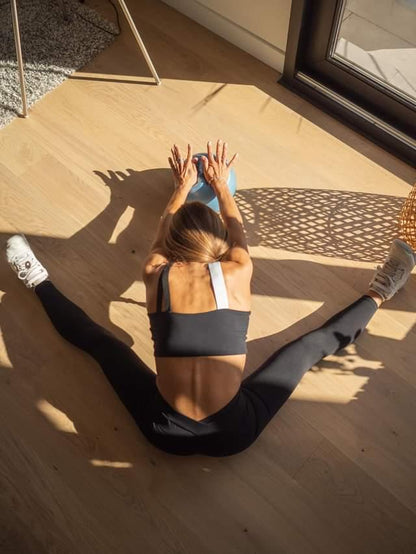 Person stretching on a wooden floor with sunlight casting shadows