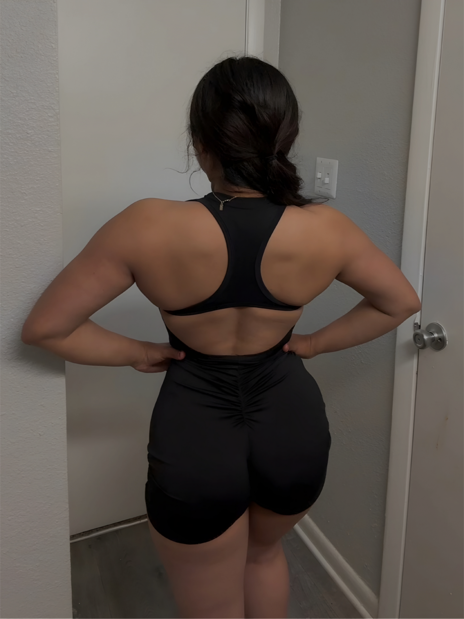 Person wearing a black athletic outfit standing in a room.