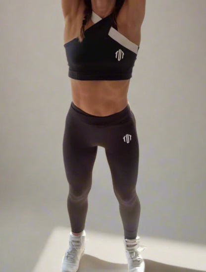 Woman in workout attire stretching in a room with plants and large windows.