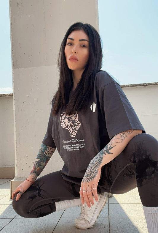 Woman wearing a dark gray t-shirt with a tiger graphic and text, sitting on a rooftop.